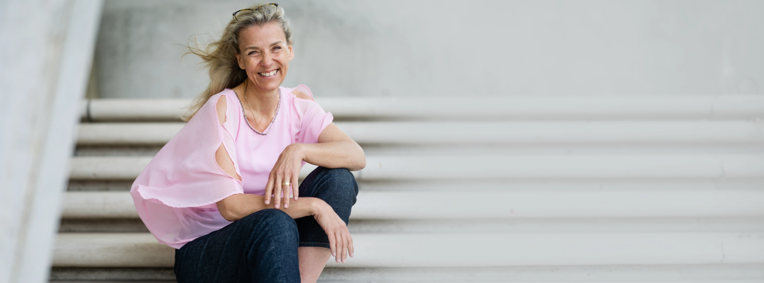 Rosa seitlich sitzend lachend auf grauer Treppe